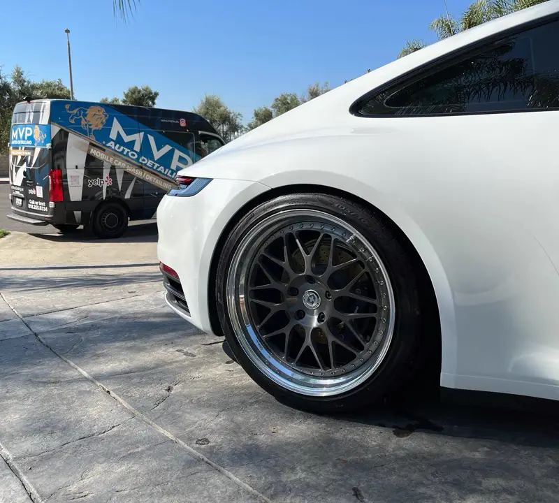 A white Porsche 911 next to the MVP van
